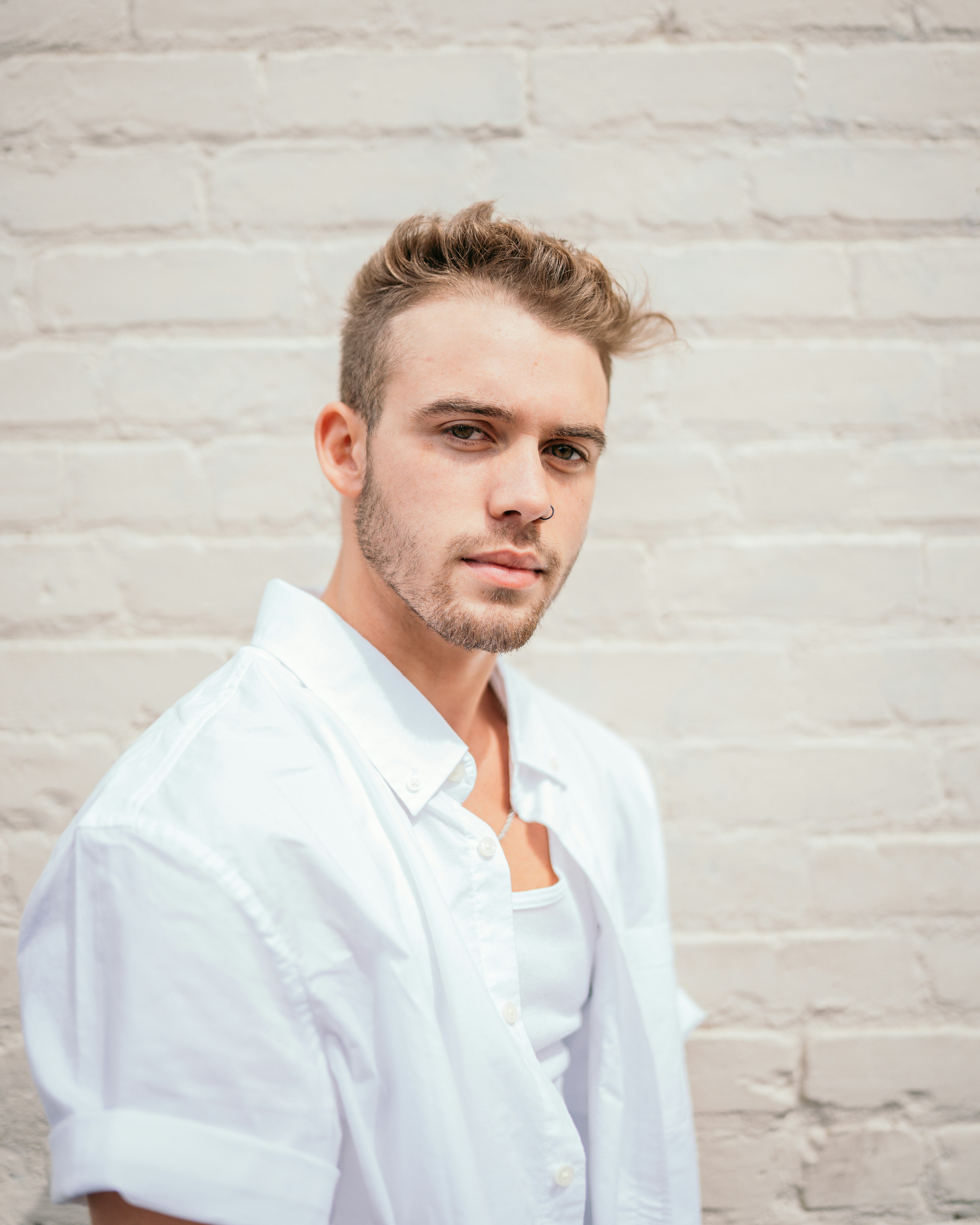 man in white button up shirt standing beside white wall